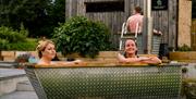 Two ladies relax in an outdoor shared tub