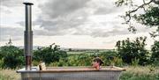 A lady reclines in the hot tub with views of the countryside in the backdrop