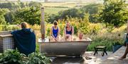 three people sit in the shared tub while others look on