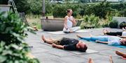 a woman leads an outdoor yoga practice in the countryside