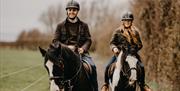 a man and woman on horseback on a countryside trail