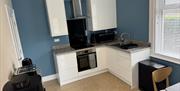 Kitchen with oven, hob, sink, cupboards and coffee machine