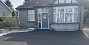 Detached bungalow with red hipped roof and private parking area and garden to front