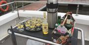 a trolley on a boat holds a bottle of whiskey as well as whiskey glasses with lemon and cloves