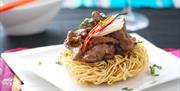 an Asian-inspired food dish with beef on top of noodles