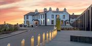 The Causeway Hotel bar accompanied by a beautiful pink and orange sunset in the background.