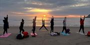 a group of women doing sunrise yoga on the beach