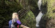 a woman stops to admire the waterfall in Glenariff Forest Park