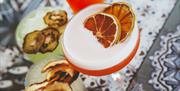 cocktails topped with dried fruits sit on a table