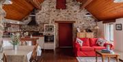 Kiln Wing kitchen and living room, featuring high ceilings, and stone walls. Also dining table, 2 red sofas by the window