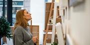 A woman looks at art on the gallery wall