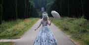 woman in a princess dress surrounded by a forest path