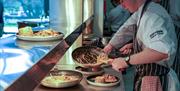 a chef works at a serving station with a frying pan