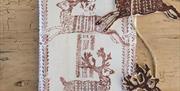 A piece of linen sitting on a wooden surface has been printed with ink using deer-shaped printing blocks on a string