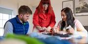 two people sitting and watching as a felt artist does a demonstration between them