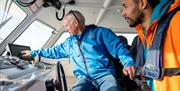 The guide/skipper of the boat showing a guest the instruments on the boat as part the Giant Shipwrecks of the North Coast experience with Carrick-A-Re