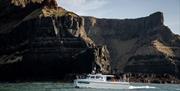 The Aquaholics boat used in the Giant Shipwrecks of the North Coast experience with cliffs in the background