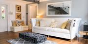 Cozy reception room at The Willows featuring a white leather sofa, yellow and grey throw pillows, a large mirror, and a black patterned ottoman.