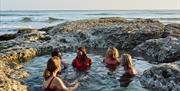 a group of women relax in a natural outdoor rock pool