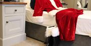 Santa's red suit and boots on a bed at The Causeway Hotel