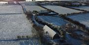 An aerial view of the studio on a Snowy winter day with the snow glistening on the curved roof.