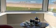 Seating area in front of window overlooking the beach and sea.