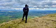 A hiker stands atop a mountain admiring the view