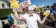 A man in a white shirt and hat selling bags of yellowman