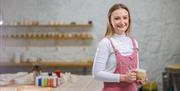 Zara McLaughlin holds an original ceramic mug creation in her workshop