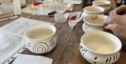 ceramic pots with various designs sit on a wooden table