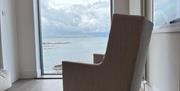 Image of chair placed at window with sea view