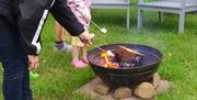 a family toast marshmallows ovet the fire pit at Flesk Water Camping