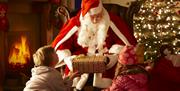 Santa claus giving a present to two children