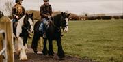 a man and woman on horseback in the countryside