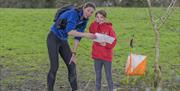 a woman and child orienteering beside a field