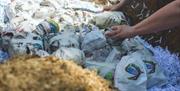 peoples' hands work at pots wrapped in newspaper