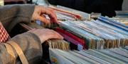 a person's hands flips through a crate of vinyl records