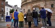 people are gathered outside Coleraine Town Hall listening to a talk by a tour guide