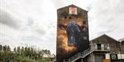 mural of a black cow on the side of a tall building