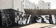 a black and white mural Henry McCullogh and a group of people on a wall, with Dominic College in the background