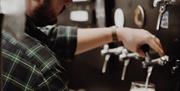 a man pours beer from a tap into a pint glass at Lacada Brewery