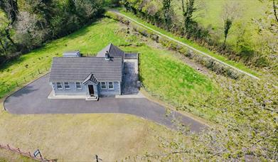 Aerial view with green woodland, with tall trees surrounding the property in a rural countryside setting.