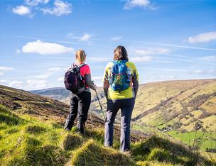 two hikers admire the view of the countryside from atop a hill