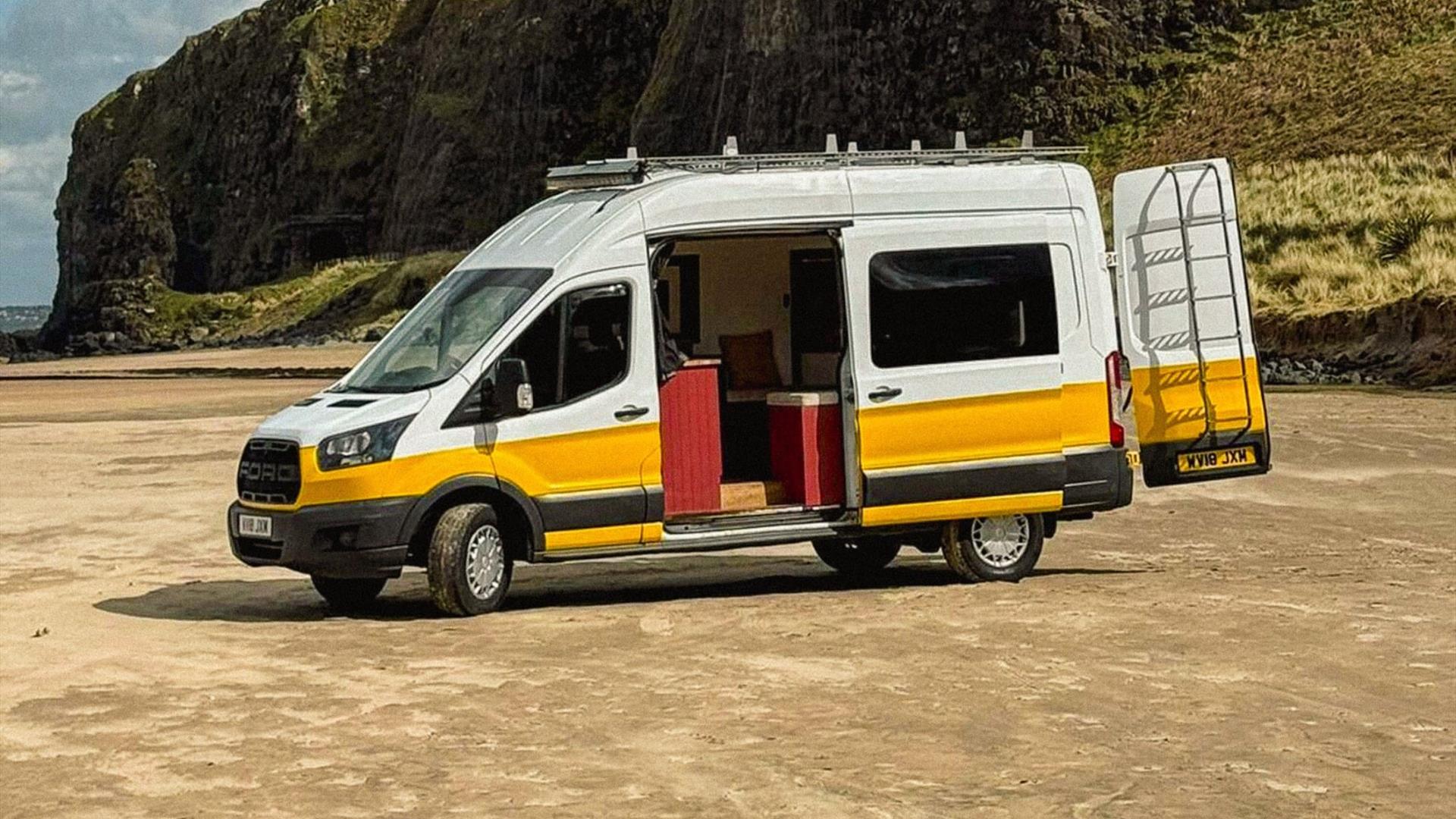 A white and yellow Karen & Co. campervan with its side door open on Downhill beach, below the cliffs A white and yellow Karen & Co. campervan with its side door open on Downhill beach, below the cliffs