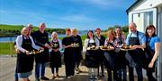cookery class students stand outdoors holding their pans of freshly cooked paella
