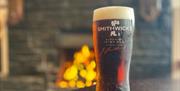 A pint by of Irish Ale with a lit fire in the background