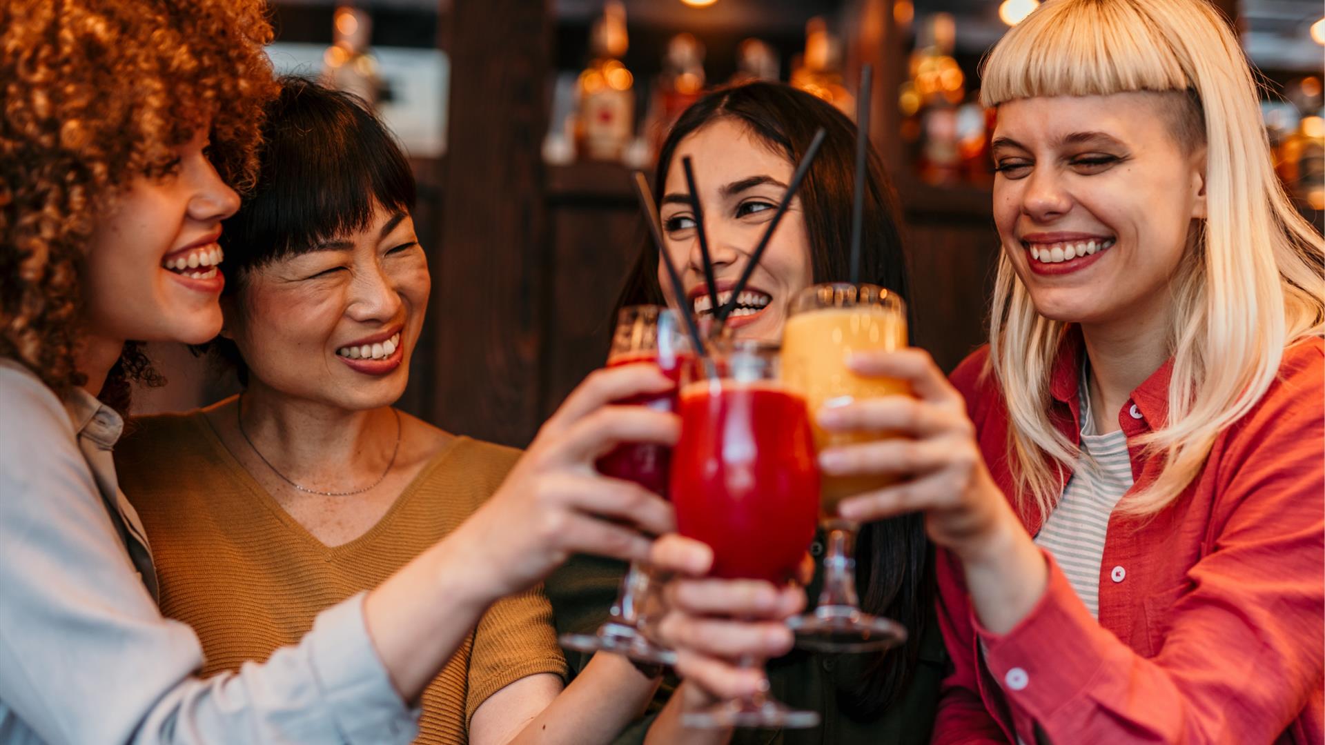 a group of women raise glasses of cocktails together a group of women raise glasses of cocktails together