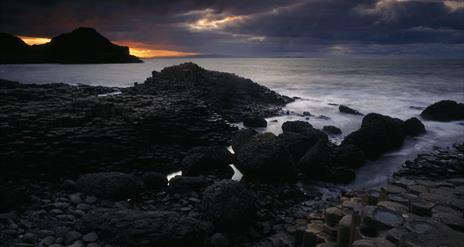 Image shows the Giant's Causeway as the sun sets in the distance