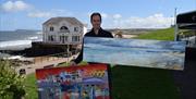 Adrian stands with his paintings in front of the Arcadia building