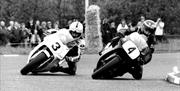 black and white iconic Image of the Dunlop motorcycle riders riding at an angle going around a sharp bend on the road